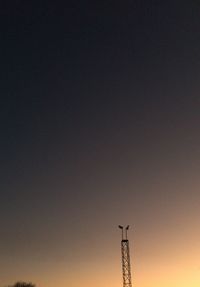 Low angle view of silhouette communications tower against sky during sunset