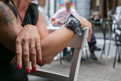 Midsection of woman sitting on chair at cafe