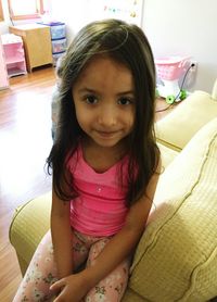 Portrait of girl sitting on bed at home