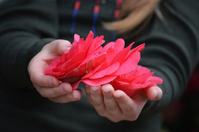 Close-up of hand holding red rose flower