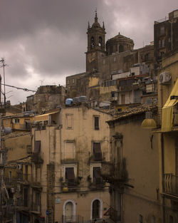 Buildings in city against cloudy sky