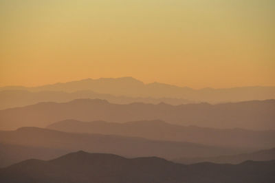 Scenic view of silhouette mountains against orange sky