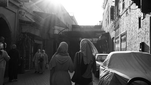 Rear view of people walking on street amidst buildings in city