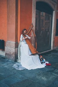 Woman holding umbrella against building