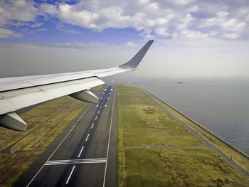 Airplane flying over airport runway against sky