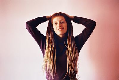 Portrait of a young woman standing against wall