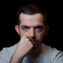Close-up portrait of young man against black background