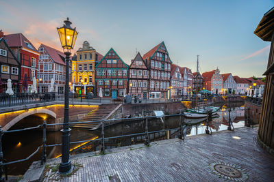 Buildings by river against sky in city