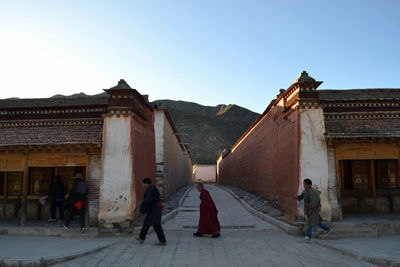 Rear view of people walking on historic building against clear sky