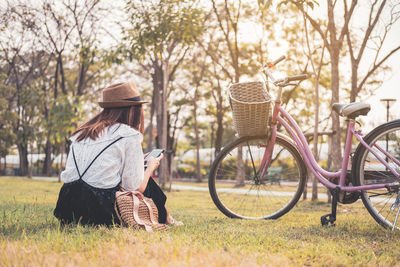 Rear view of woman with bicycle in basket against trees