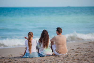 Rear view of woman sitting at beach