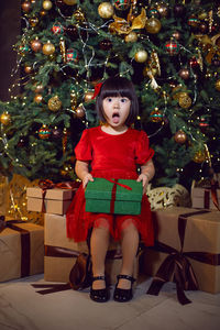 Portrait of a beautiful korean girl child in red dress at christmas with box of gifts christmas tree