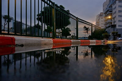 Reflection of bridge in puddle on city at dusk