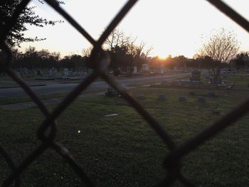 Close-up of chainlink fence against sunset sky