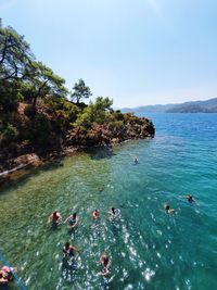 High angle view of people swimming in sea against sky