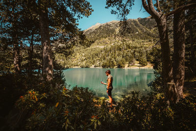 Man standing by lake against trees