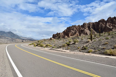 Road leading towards mountains against sky