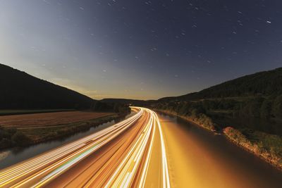 Light trails on road against sky at night