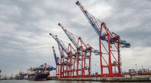 Cranes at commercial dock against sky