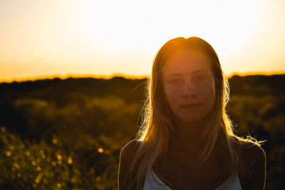 Portrait of young woman standing on field against sky