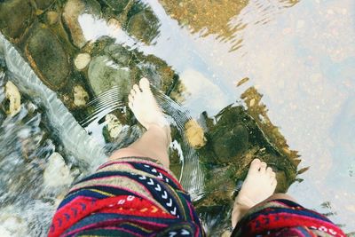 Low section of woman standing in river