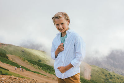 Portrait of smiling boy standing against sky