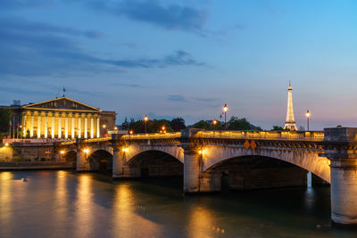 Illuminated bridge over river against sky at night