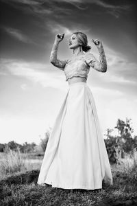 Woman with umbrella standing on field against sky