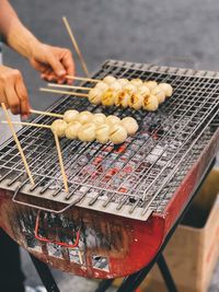 Midsection of person preparing food on barbecue grill