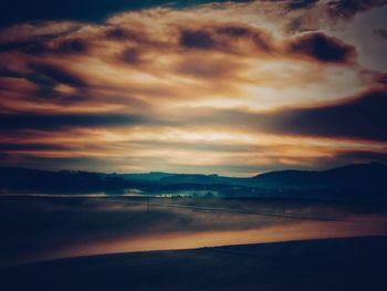 Scenic view of sea against cloudy sky at sunset