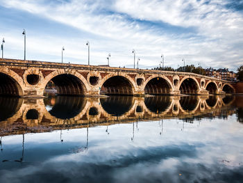 Arch bridge over river against sky