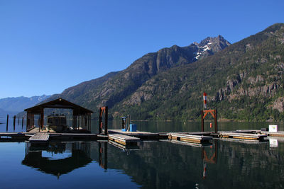 Boat by pier at lake chelan against mountains and clear blue sky on sunny day