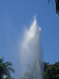 Low angle view of waterfall against clear blue sky