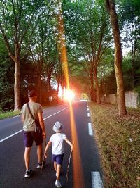 Rear view of people on street amidst trees