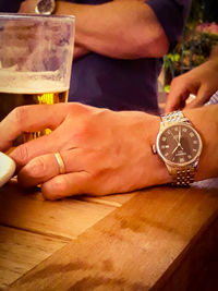 Midsection of couple holding glass at table