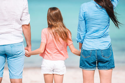 Rear view of family standing on beach