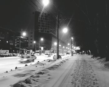Road passing through snow covered city at night