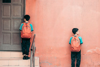 Rear view of boys with backpacks standing outside school