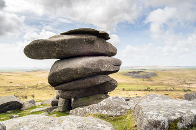 Stack of stones on field against sky