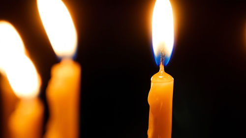 Close-up of lit candle against black background