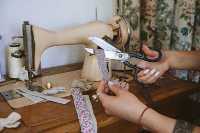 Cropped hand of woman using sewing machine