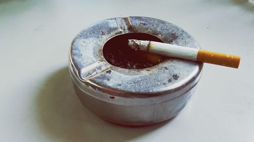 Close-up of cigarette in metallic ash tray on floor