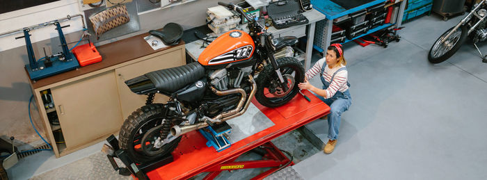 Mechanic woman reviewing custom motorcycle over platform