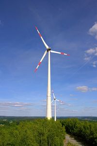 Low angle view of wind turbines against sky