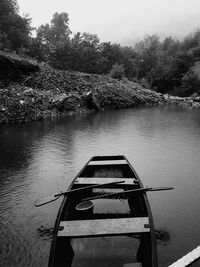 Boat moored on lake against trees