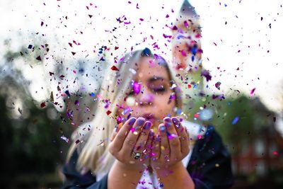 Woman blowing confetti outdoors