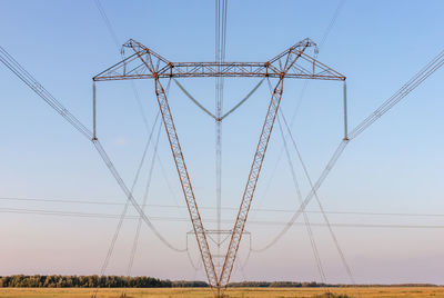 Low angle view of electricity pylon on field against sky