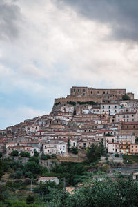 Rocca imperiale, low angle view of village against cloudy sky