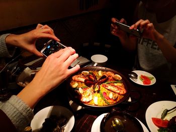 Cropped hands photographing food from mobile phones at restaurant