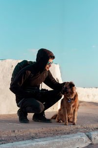 Man with dog sitting against sky